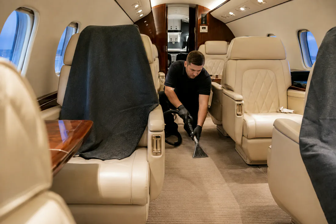 Technician performing a low-moisture carpet extraction inside an executive jet cabin